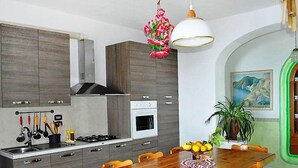 Cozinha moderna com armários de madeira, fogão a gás e área de jantar com mesa e cadeiras de madeira.
