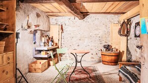 Une pièce rustique avec des poutres en bois, une table, des chaises, un buffet et un tonneau.