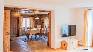 Un intérieur moderne comprenant un coin repas, un plancher en bois, un téléviseur à écran plat et un espace salon confortable.