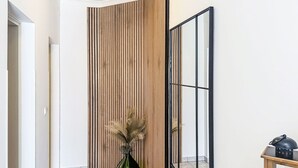 A hallway with a wooden slat wall, a green vase with pampas grass, a bench, and a lantern. - Apartment Tea by Interhome (Umag/Murine)