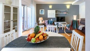 A modern living room with a dining area, featuring a fruit bowl on the table, a sofa, a TV, and a cabinet. - Apartment Tea by Interhome (Umag/Murine)