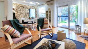 A spacious living room with a dining area, a stone wall, and a large sliding glass door to the outdoors. - Apartment Tea by Interhome (Umag/Murine)