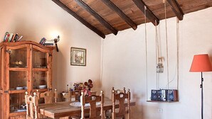 A rustic dining room with a wooden table and chairs, a wooden cabinet with dishes, and a vintage radio.