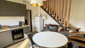 Una cucina moderna con forno integrato, un'area pranzo con un tavolo rotondo e quattro sedie, e una scala in legno.