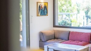 Un salon moderne avec un plafond en bois, une grande fenêtre, un canapé gris, un divan rayé rouge et blanc, et une table basse en bois.