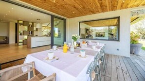 Un vaste espace dédié à la salle à manger, avec un plafond en bois, une grande fenêtre et une vue sur l’extérieur.