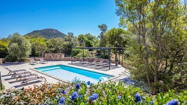 Une piscine avec des chaises longues, une pergola et une vue imprenable sur les montagnes.