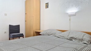 Une chambre à coucher avec un lit, une chaise, une armoire et une prise de courant au mur.