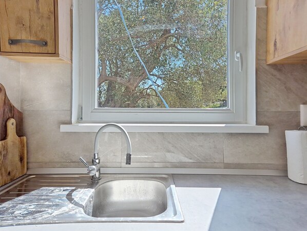 A kitchen with a window, a sink, and wooden cabinets.