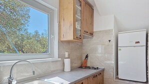 Une cuisine avec une fenêtre, un évier, des placards, une cuisinière et un réfrigérateur.