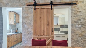 Une cuisine moderne avec des meubles en bois, un mur en pierre et une porte coulissante de style rustique.