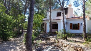 A rustic house with a stone pathway leading to the entrance, surrounded by trees and a clear sky. - Villa Pinos by Interhome (L'Ametlla de Mar)