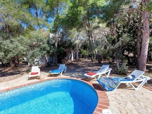 Un espace piscine avec des chaises longues et une piscine carrelée.