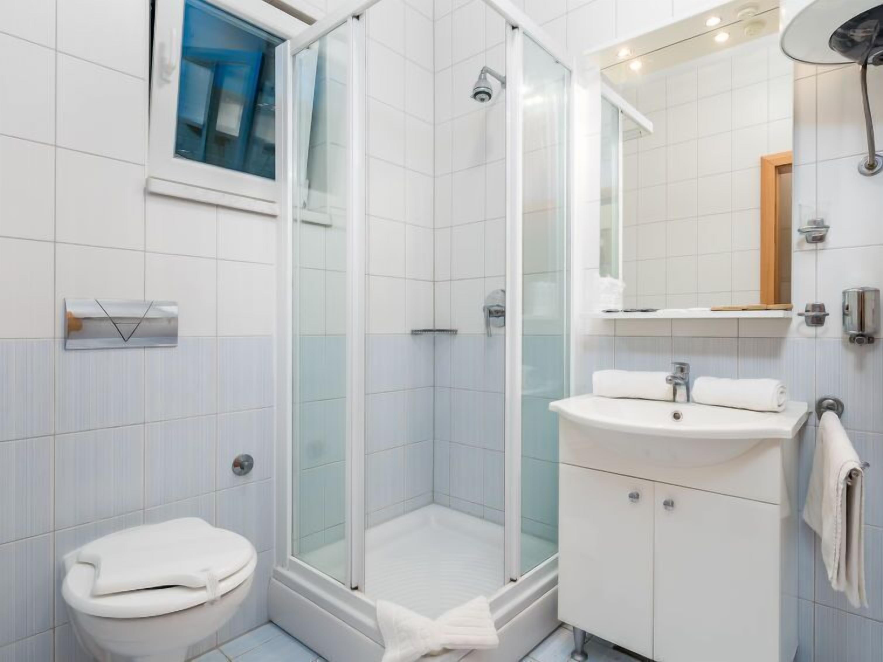 Un bagno moderno con doccia vetrata, un lavandino bianco e un water.