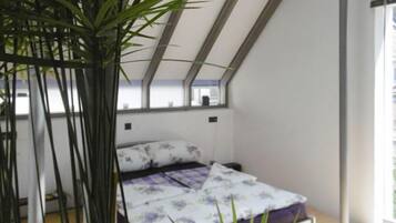 Un dormitorio con cama, ventana y planta.