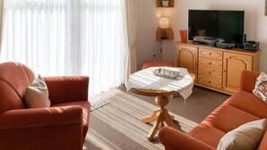 Una sala de estar con sofá, mesa de centro, televisor y aparador.