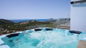 A hot tub with a panoramic ocean view, surrounded by a modern building with a glass railing. - Finca Edel by Interhome (Moraira)