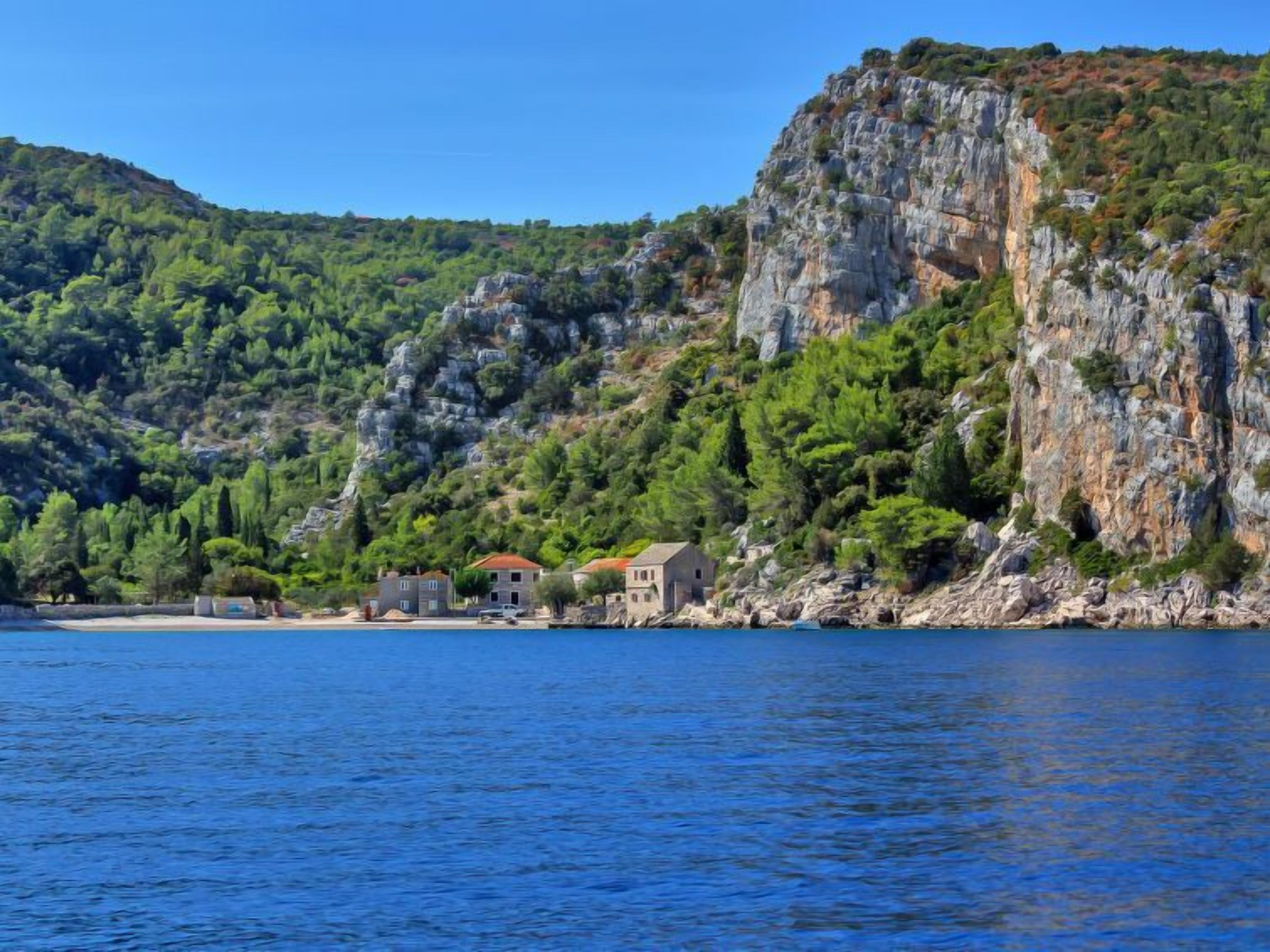 A coastal property with a rocky cliff and a clear blue sea.