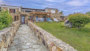 A stone pathway leading to a stone house with a covered patio area and outdoor seating.