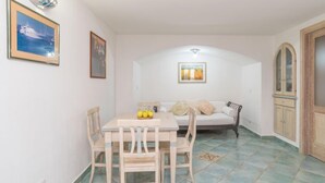 A dining area with a table and chairs, a sofa, and a cabinet.
