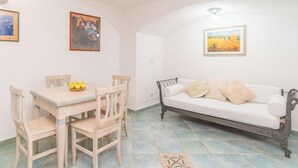 A room with a dining table, chairs, a sofa, and artwork on the walls.