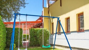 A swing set in a backyard with a yellow building in the background.