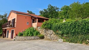 Una casa de dos pisos con un muro de piedra y un balcón.