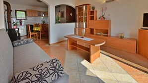 Un espacio habitable compacto con sofá, mobiliario de madera, una zona de cocina y una mesa de comedor.