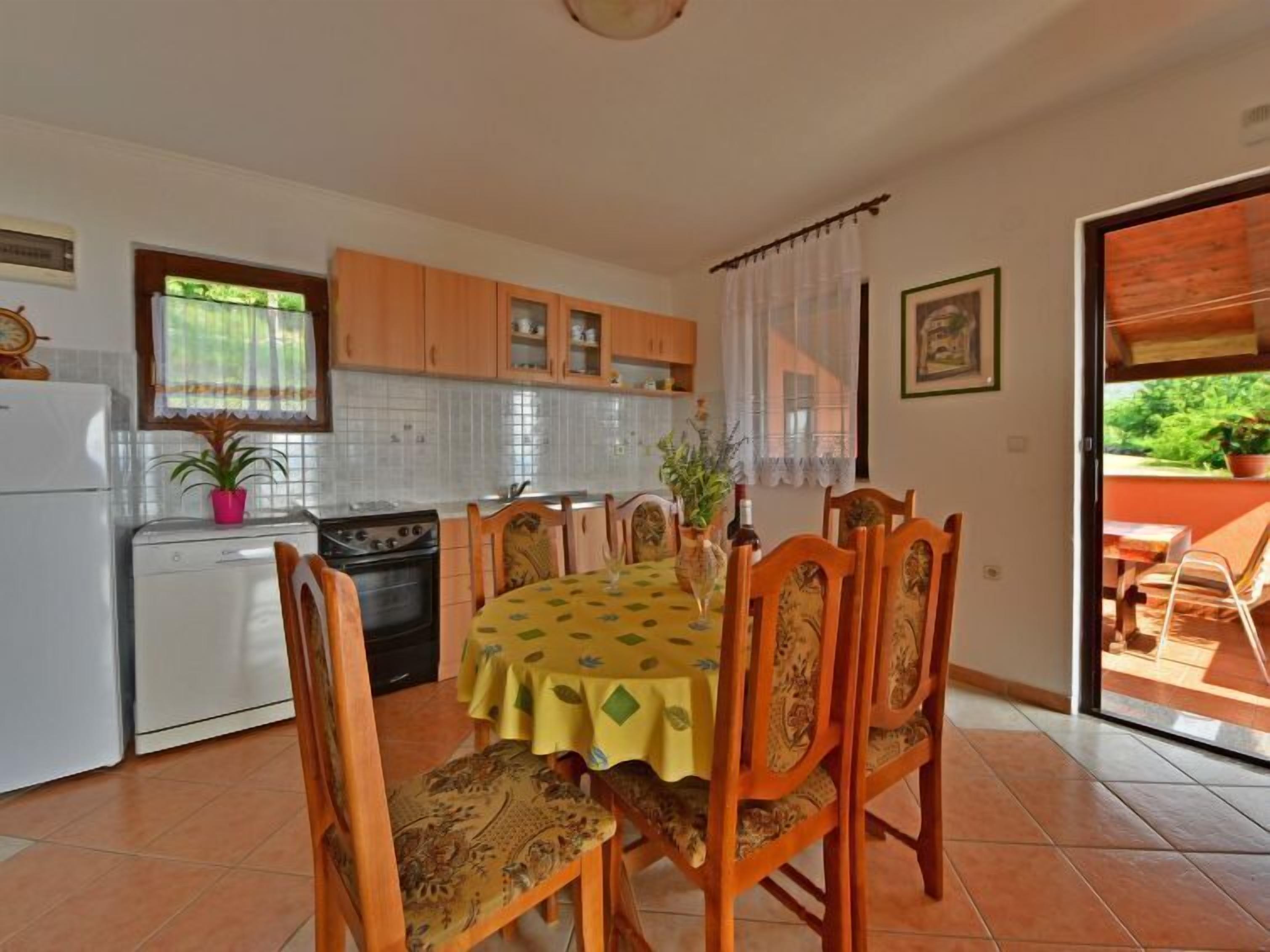 Une cuisine compacte avec un coin repas, comprenant une table avec des chaises, une cuisinière et un réfrigérateur.