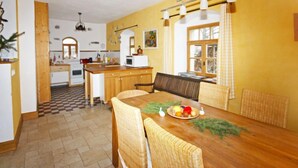 Una cucina compatta con mobili in legno, un tavolo da pranzo con sedie in vimini e un pavimento a scacchi.