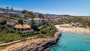 Un poble costaner amb un litoral rocos, una platja de sorra i edificis residencials.