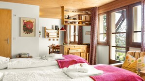 Une chambre confortable avec deux lits, un plafond en bois, un bureau avec une chaise et une fenêtre avec des rideaux.