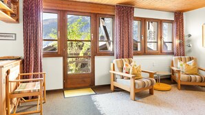 Une pièce chaleureuse, meublée en bois, avec de grandes fenêtres et une vue sur les montagnes.