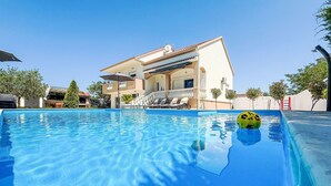 A swimming pool with a yellow ball, a white building with a balcony, and a clear blue sky. - Tina & Tino by Interhome (Zadar)