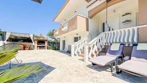A two-story building with a stone patio, outdoor seating, and a covered barbecue area. - Tina & Tino by Interhome (Zadar)