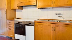 A kitchen with wooden cabinets, a stove, and a sink. - Apartment Tegola by Interhome (Bucine)