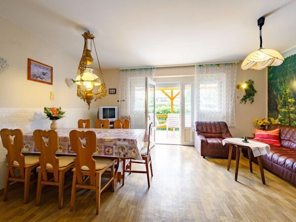 A dining area with a table and chairs, a sofa, and a television. - Cyklamen by Interhome (Balatonmariafurdo)