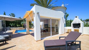 Um terraço no telhado com piscina, área de churrasco e espaço de refeições envidraçado.