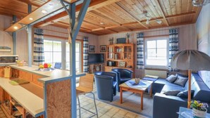 Un intérieur de chalet chaleureux comprenant un coin cuisine, une table à manger, un canapé et un téléviseur.