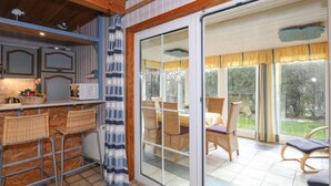 Une cuisine avec un coin bar, un espace repas avec des chaises et une porte-fenêtre coulissante donnant sur un patio extérieur.