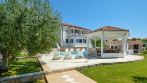 Une maison à deux étages dotée d ’un patio couvert, d’une piscine et d’une pelouse bien entretenue.
