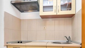 Uma cozinha com armários bege, um exaustor de aço inoxidável, uma pia e uma bancada.