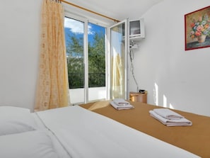 A hotel room with a bed, a small table with towels, a window with curtains, and a painting on the wall. - Apartment Rubin by Interhome (Hvar/Pokrivenik)