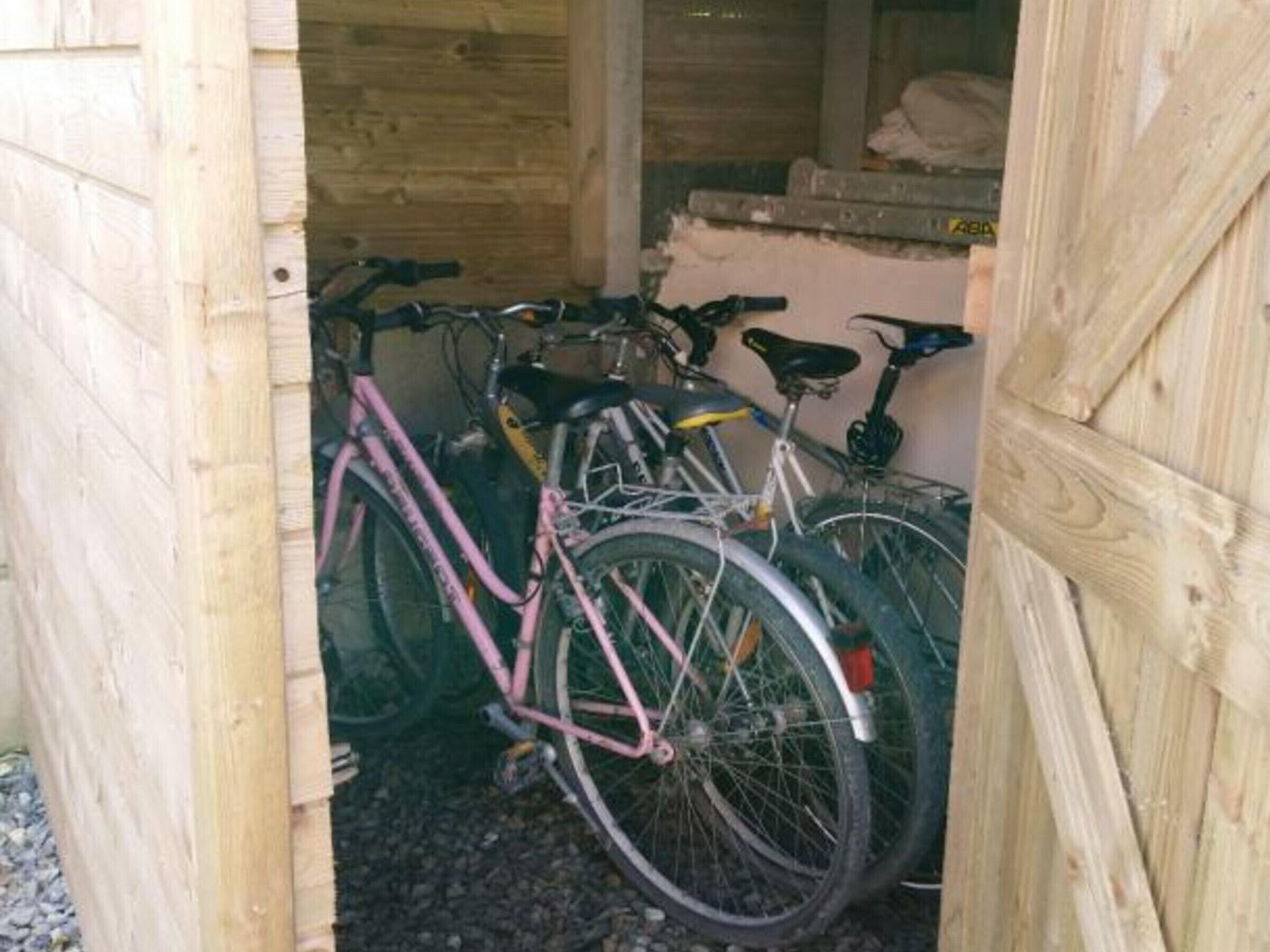 A wooden structure with a door, inside which bicycles are parked.
