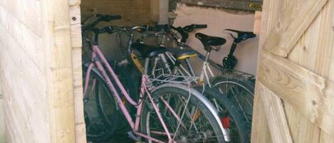 A wooden structure with a door, inside which bicycles are parked.