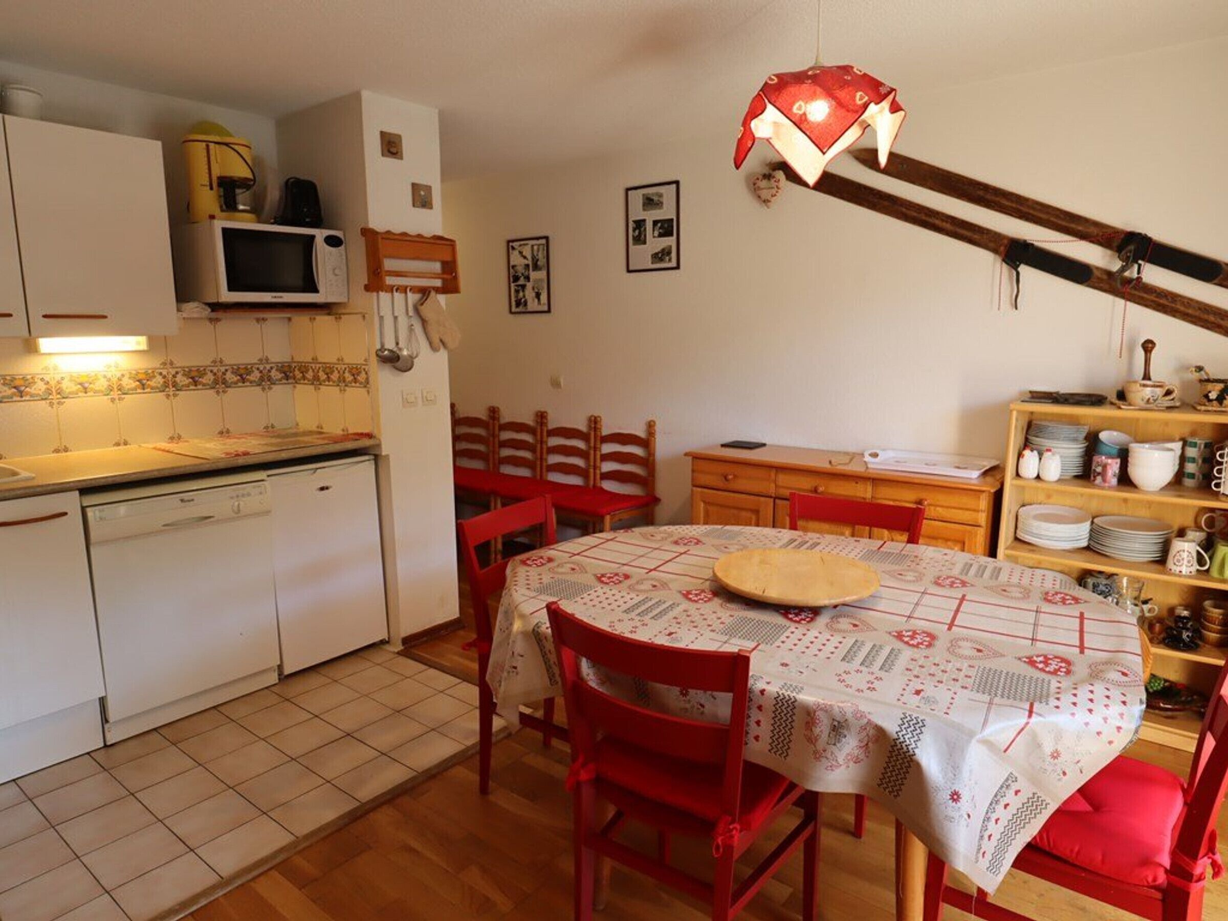 A compact kitchen with a dining area, featuring a microwave, sink, and wooden cabinets.