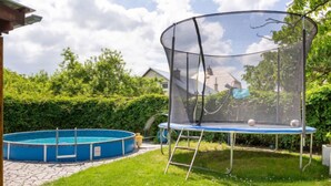 Un patio trasero con un trampolín y una piscina.