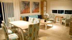 Una sala de estar moderna con comedor, que incluye un sofá, sillas, una mesa de centro y arte abstracto en las paredes.