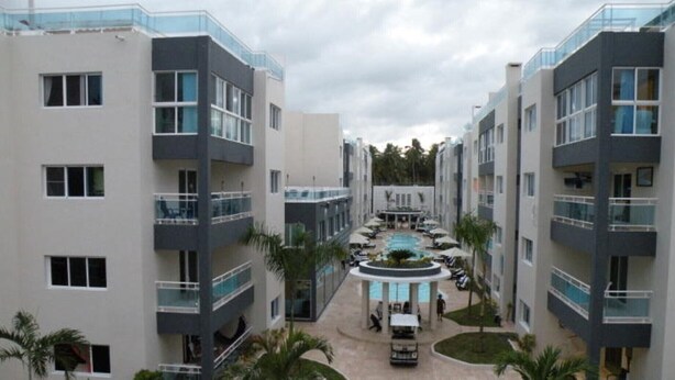 Un hotel moderno con un patio central, varios balcones y una piscina.
