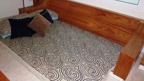 Una habitación pequeña y acogedora, con cabecera de madera, suelo estampado y una cama individual con almohadas.